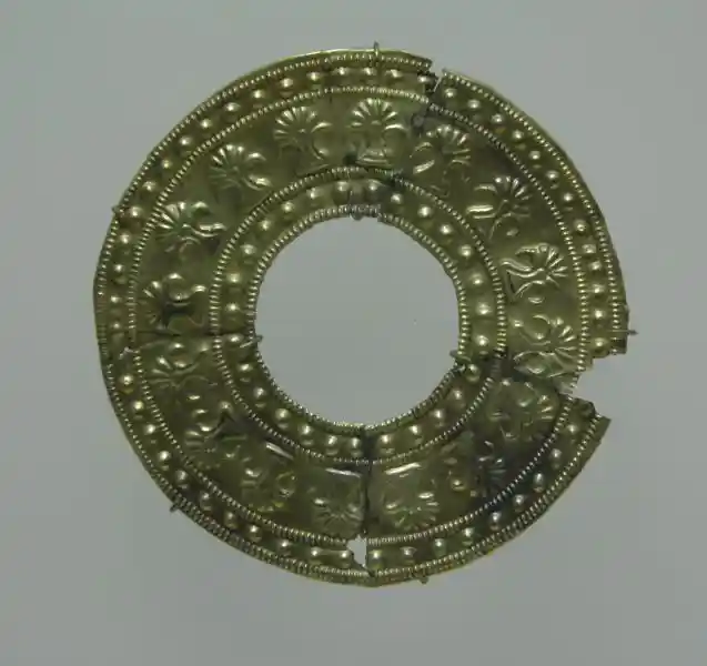 Gold circular plaque with horn-like half-sun design around the circle